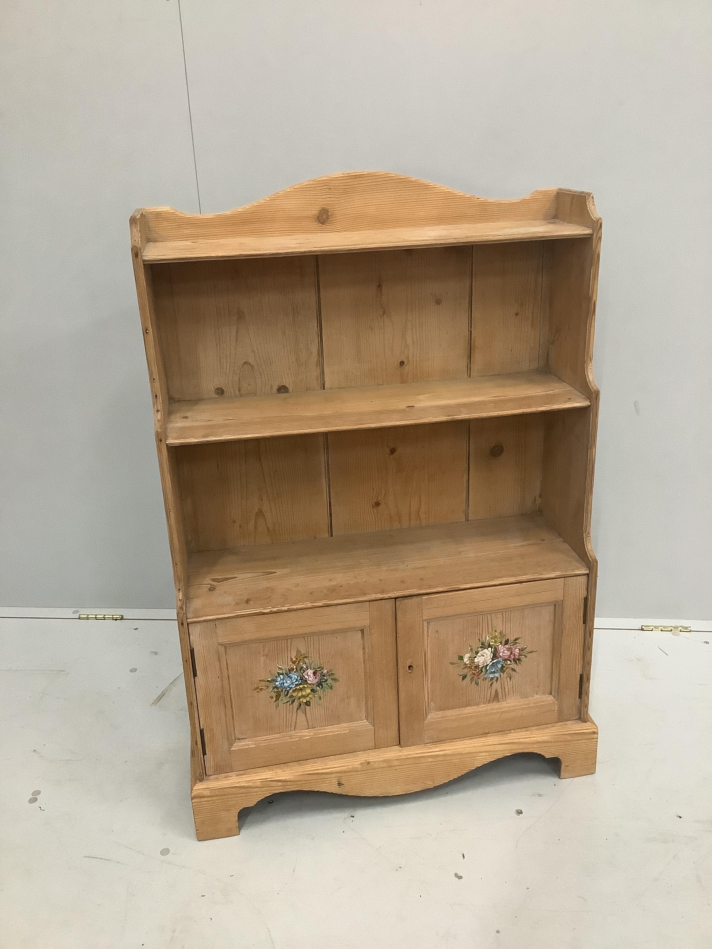 A stripped pine waterfall bookcase with stencilled doors, width 69cm, height 104cm